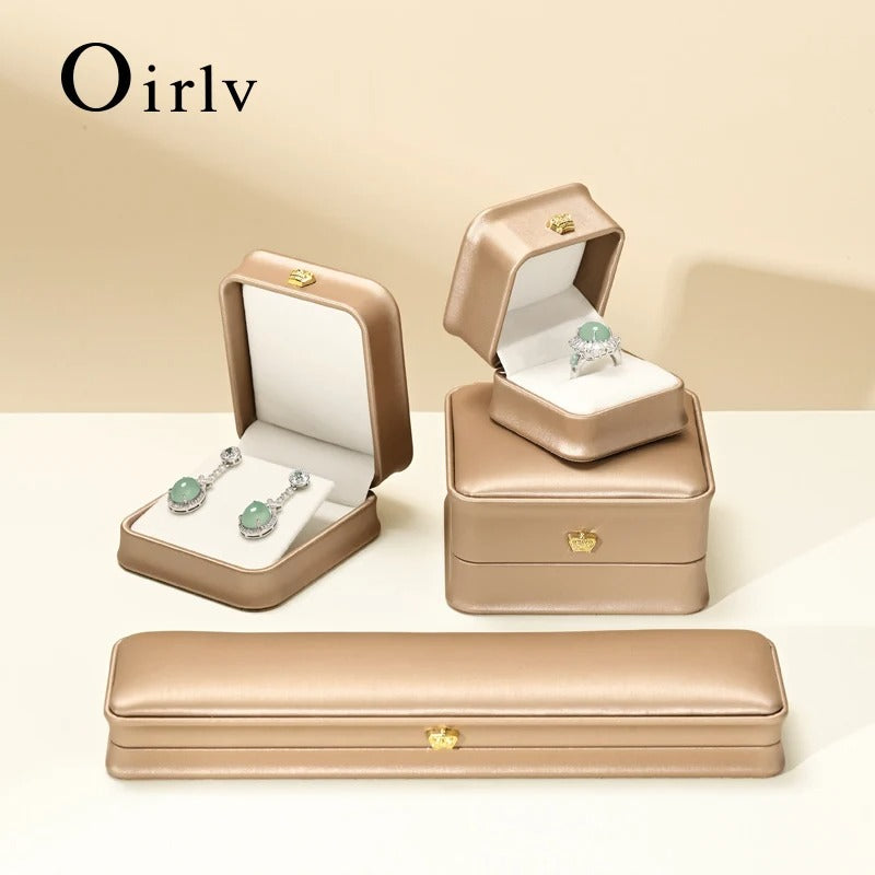 Jewelry set including earrings and a ring in beige jewelry boxes with 'Oirlv' branding.