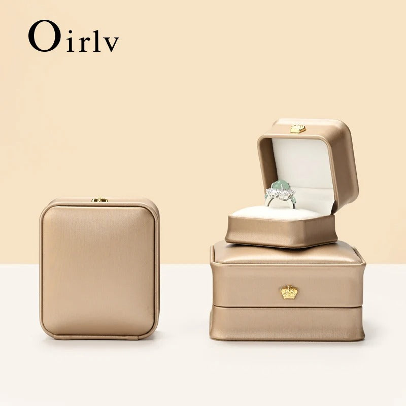 Beige jewelry box with a ring on a beige background, featuring the brand 'Oirlv'.
